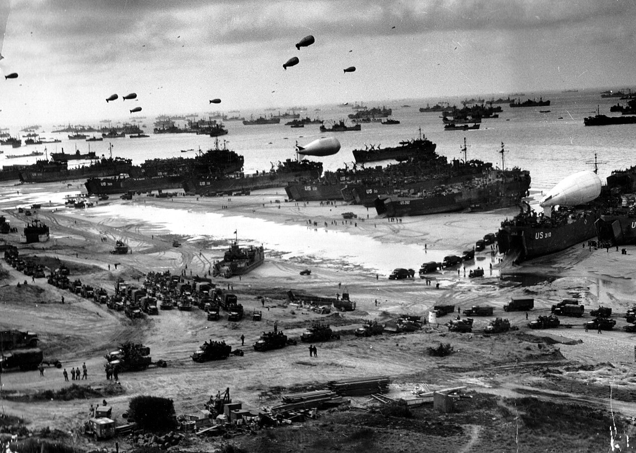 Landing ships unloading vehicles and supplies on a Normandy invasion beach in June 1944