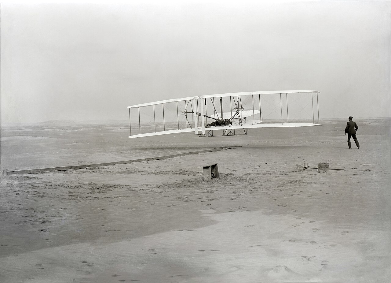 Orville Wright making the first powered controlled sustained flight at Kitty Hawk on 17 December 1903